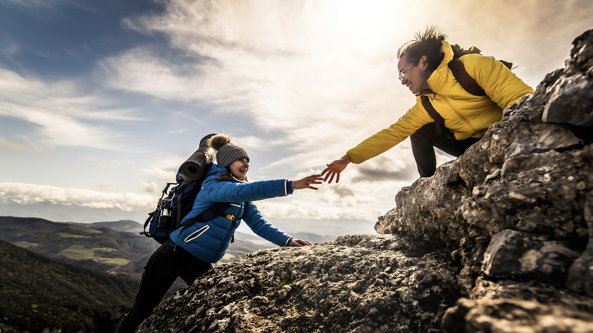 reaching to pull a teammate up the mountain